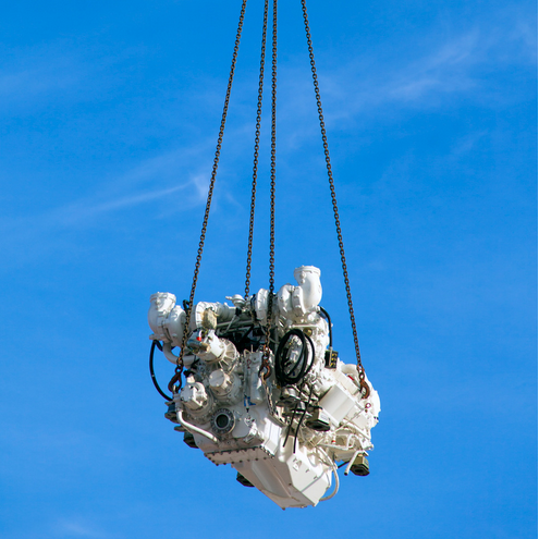 Moteur suspendu par des câbles sous un ciel bleu.